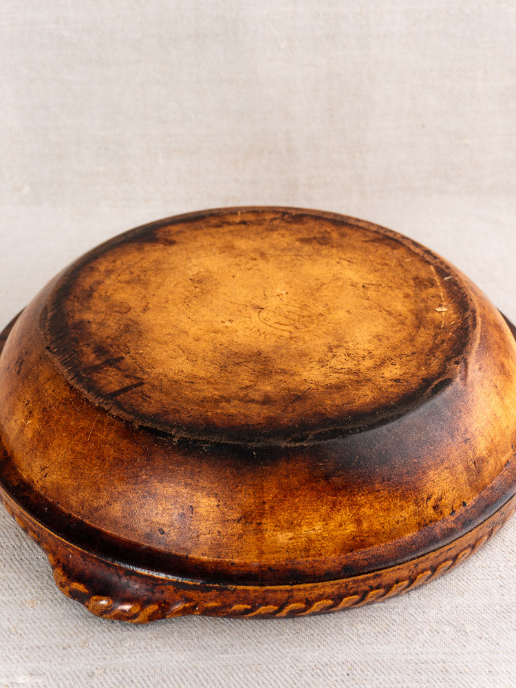 Antique French Vitry-le-François stoneware gratin dish shown upside down on neutral fabric, highlighting textured base and raised edge.