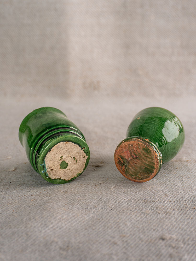 French green glazed pottery pieces from an 8-piece Provençal Terre Vernissée set on textured gray surface, bases visible.