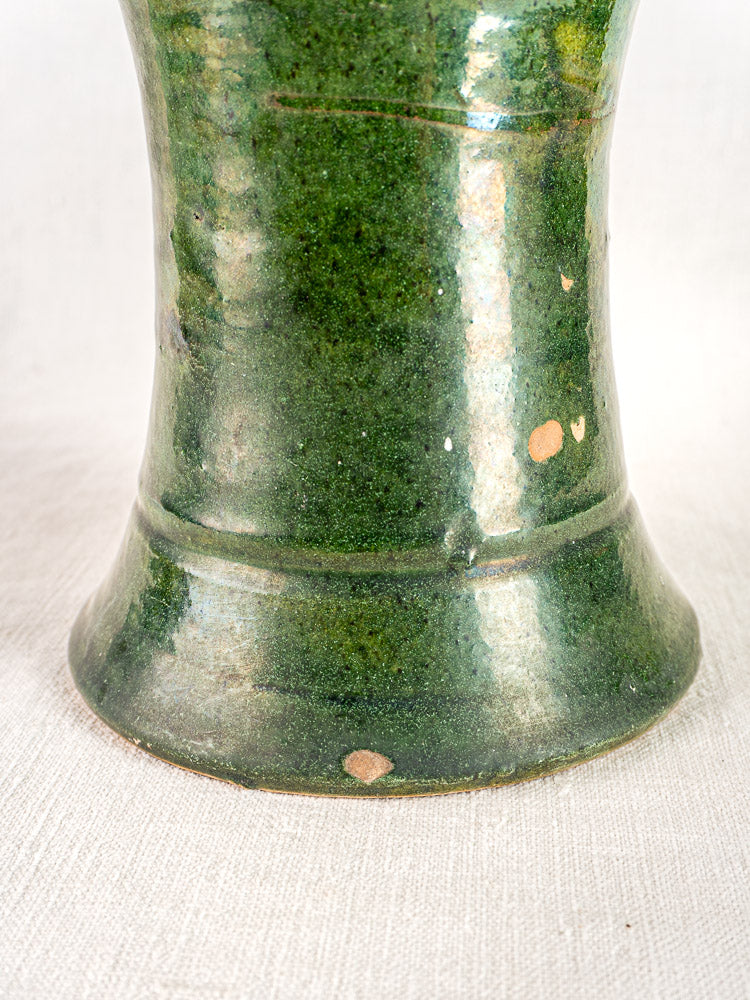 Hand-thrown antique French green glazed terracotta vase base with minor chips, on white textured fabric.