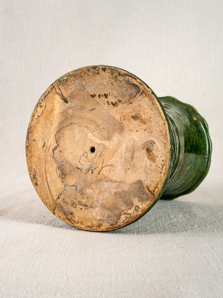 Bottom of antique French green glazed terracotta vase, rough unglazed base with earth-toned marks.