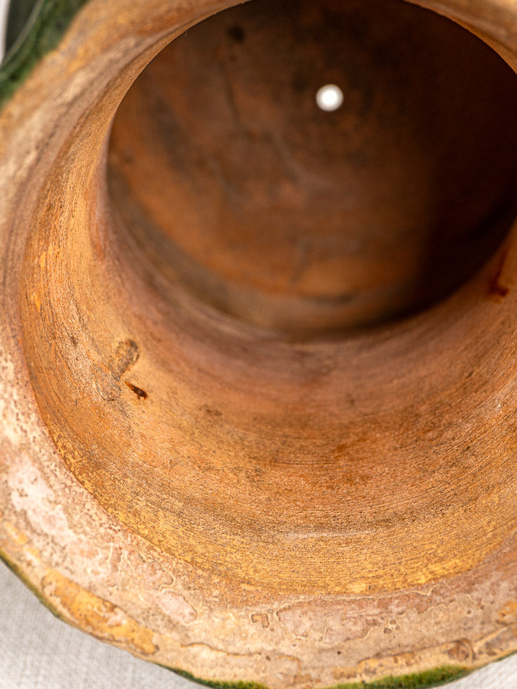 Interior detail of antique French green glazed terracotta vase with natural textures and drainage hole.