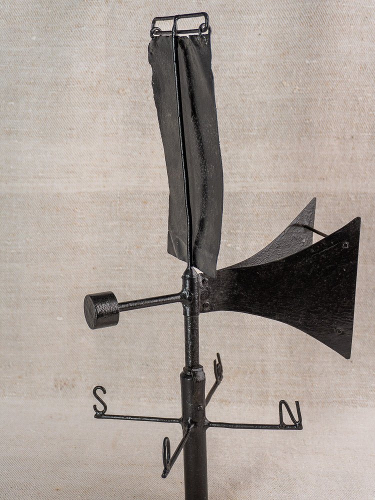 Antique French painted iron weathervane with arrow and cardinal points on neutral textured background.