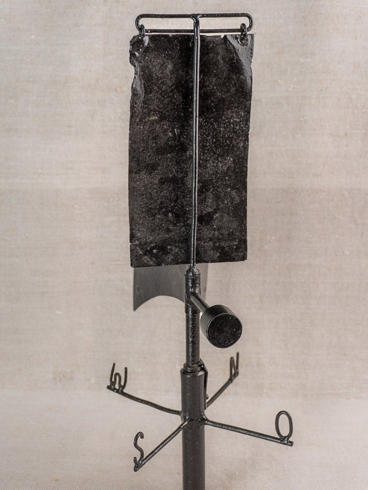 Antique French painted iron weathervane with vertical flag and cardinal compass, on neutral fabric background.