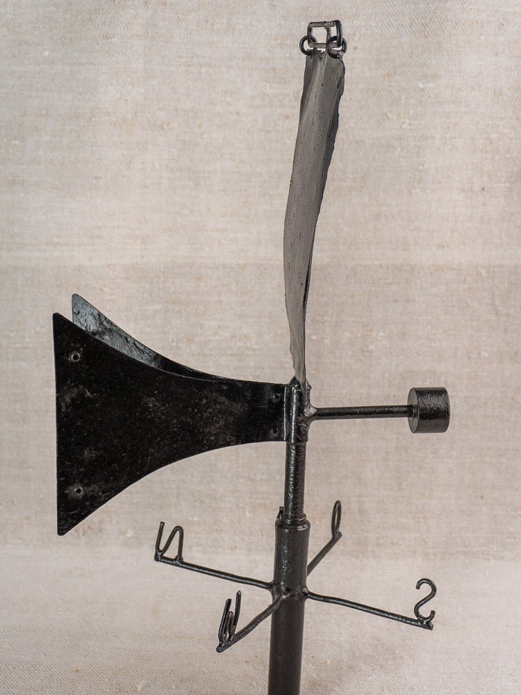 Antique French painted iron weathervane with arrow and compass details on a beige background.