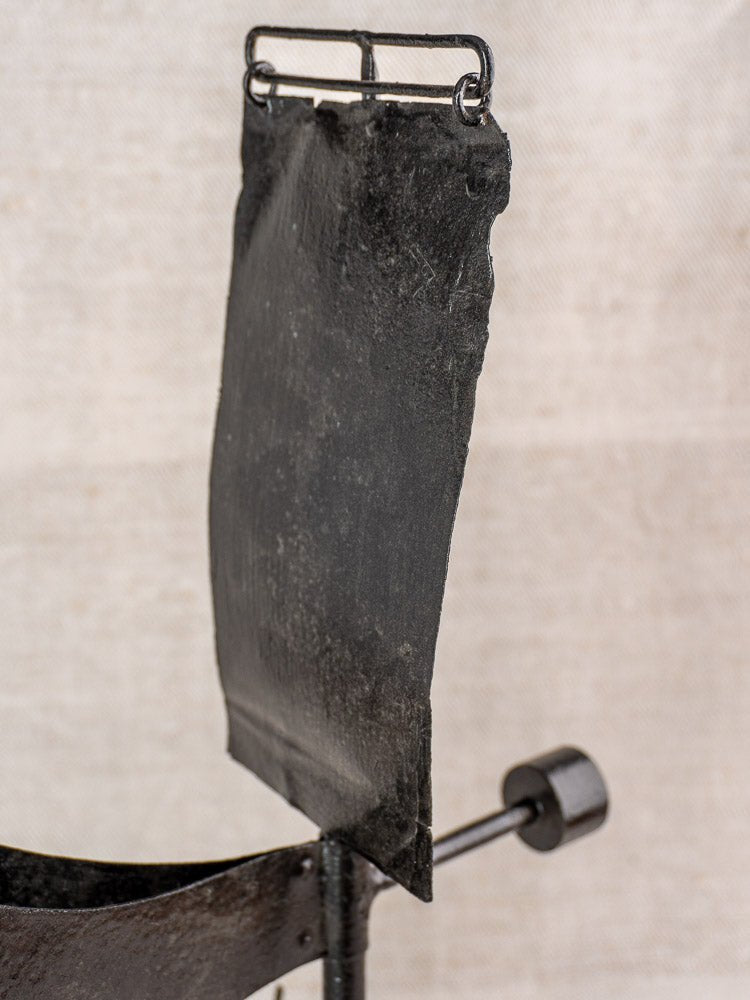Antique French painted iron weathervane with rectangular plate, cylindrical handle, and weathered patina on neutral fabric.