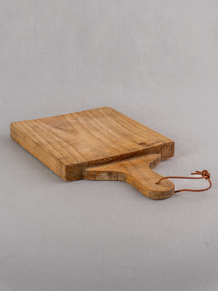 Mid-century French oak bread board with handle and brown leather loop, displayed on a light gray surface.