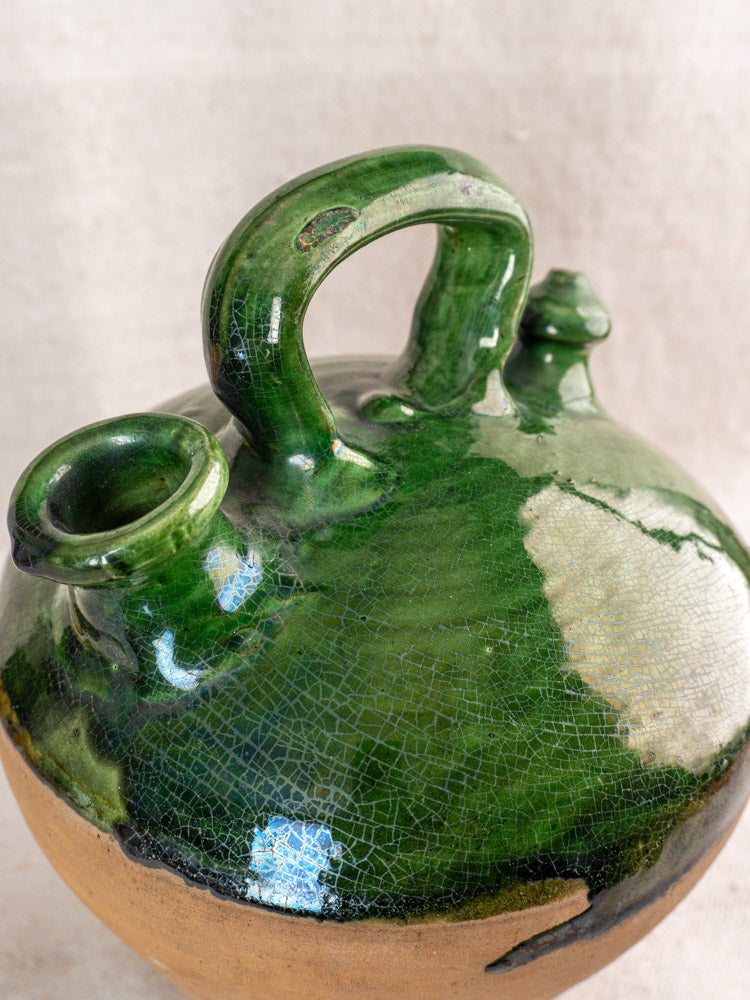 Antique French gargoulette featuring emerald green glaze, handle, spout, decorative knob, and unglazed clay base.