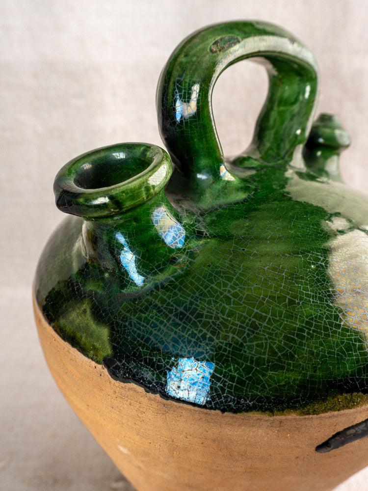 Antique French gargoulette with emerald green glaze, dual spouts, handle, and unglazed rustic brown clay lower section.
