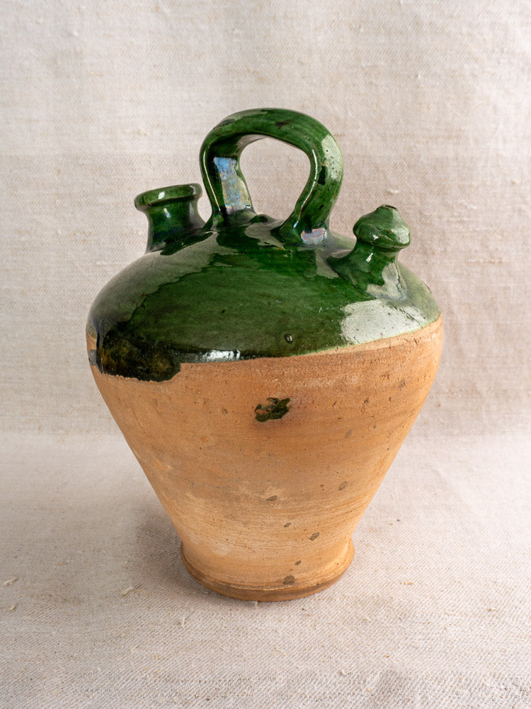 19th-century French antique gargoulette with emerald green glazed top, natural clay base, on neutral fabric background.