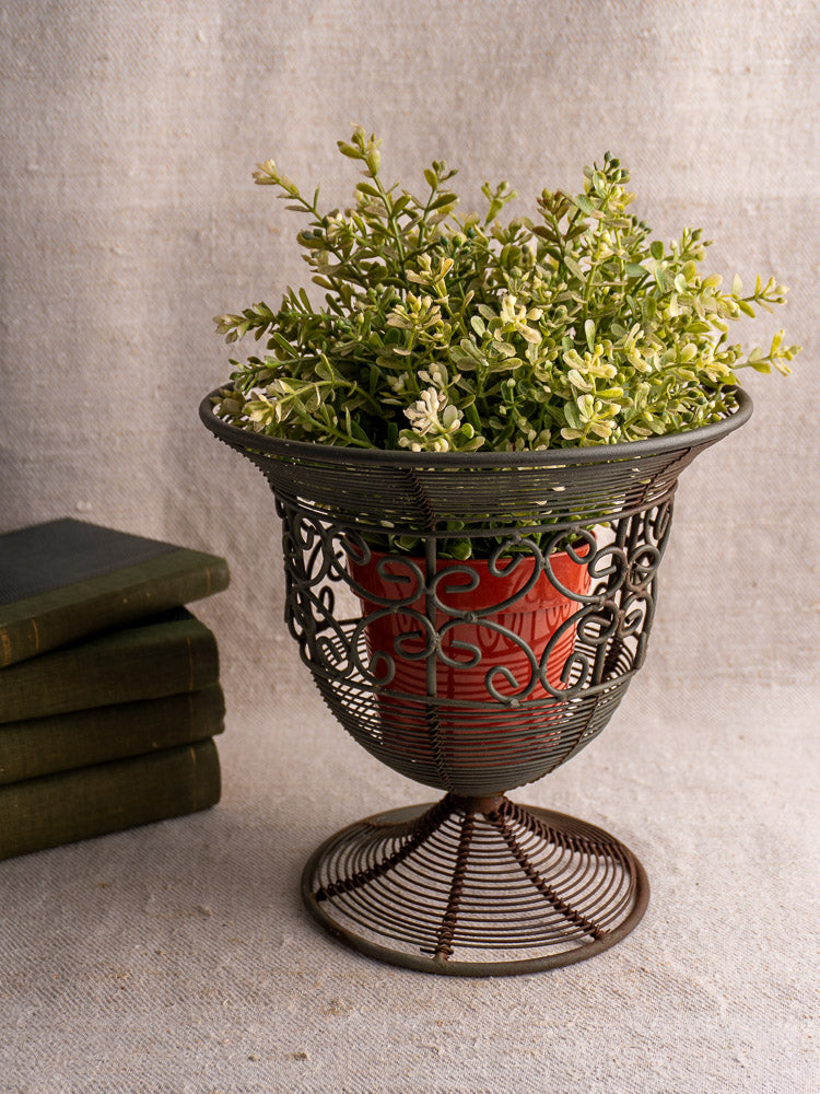 Antique French wire fruit bowl with ornate swirling design and flared footed base on neutral surface.