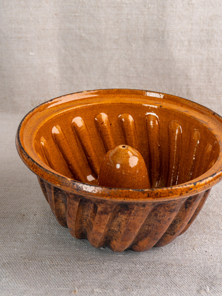 Pair of late 19th-century French Kouglof molds in brown glazed ceramic, fluted sides, on fabric.