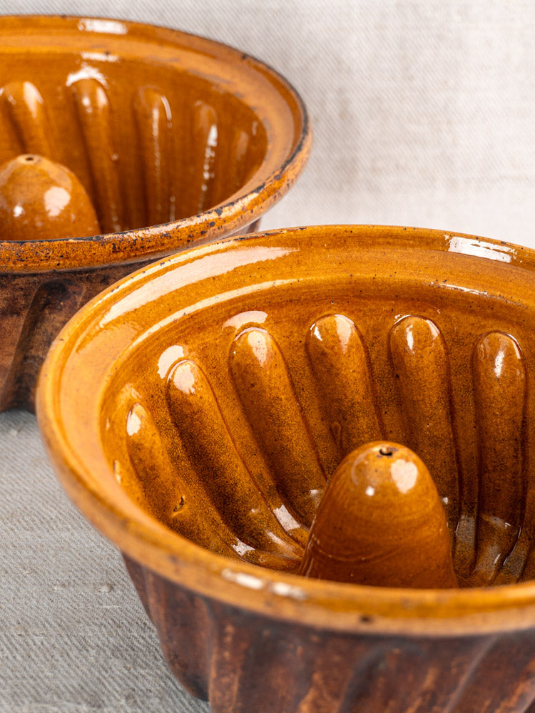 Pair of late 19th-century French Kouglof molds in glazed Alsace earthenware with brown fluted sides, on light fabric.