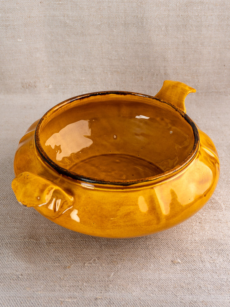 French Haute Provence yellow faience tureen with pine cone finial and two handles on beige surface.