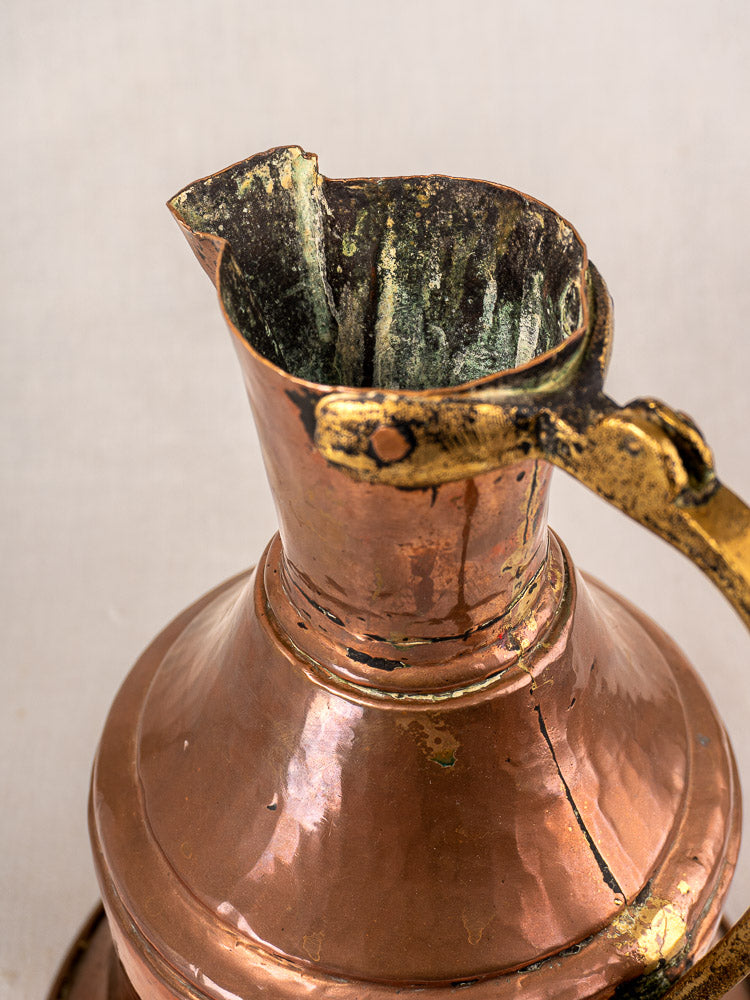 Antique French copper water jug with curved spout, brass handle, oxidized interior, and reddish-brown sheen.