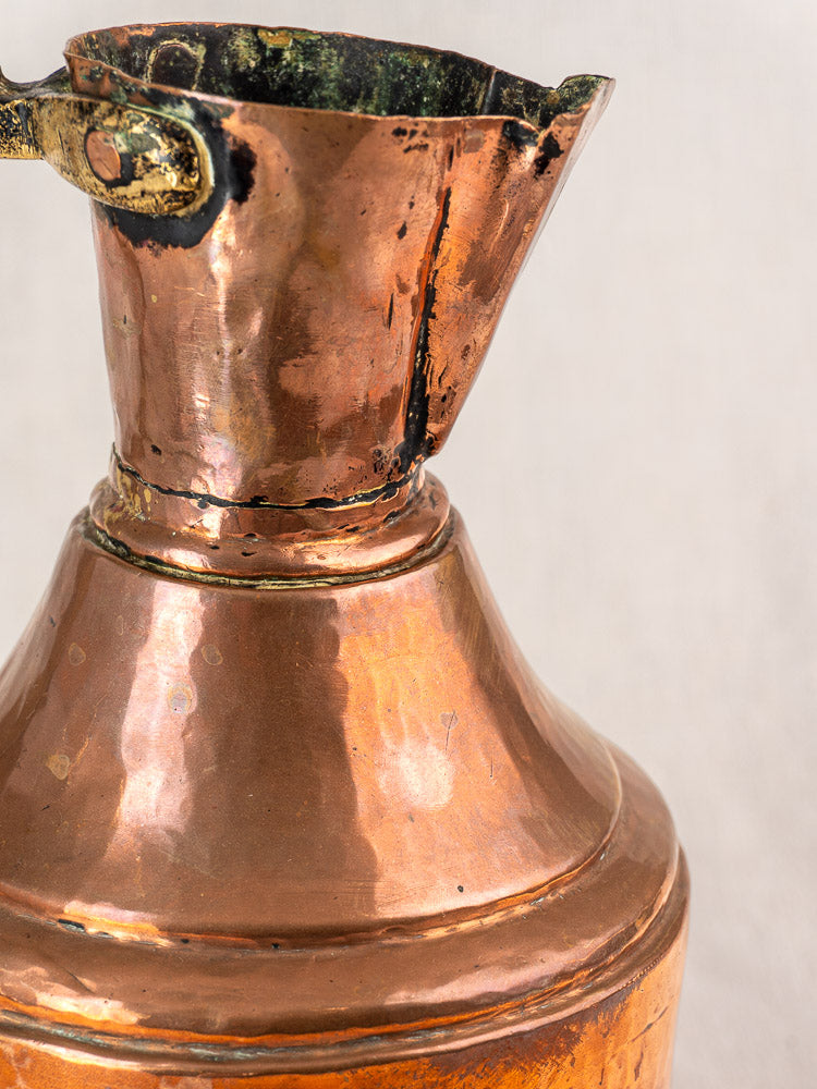 Antique French copper water jug with wide spout, curved brass handle, and rich 19th-century patina.