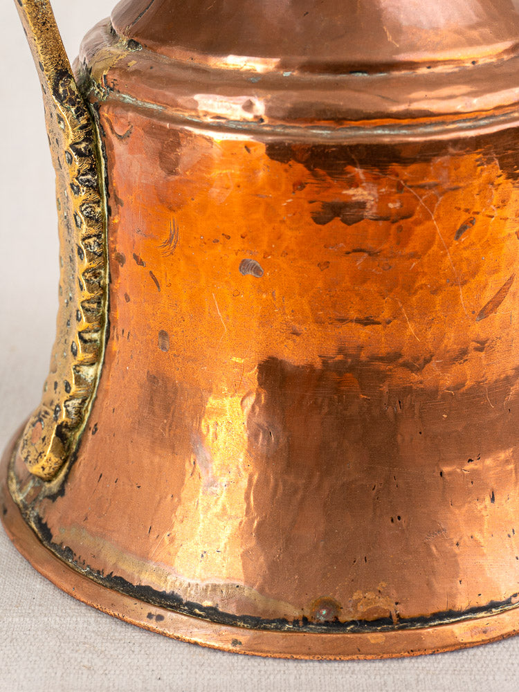 19th-century French copper water jug with ornate brass handle, textured surface, warm sheen, and aged patina.