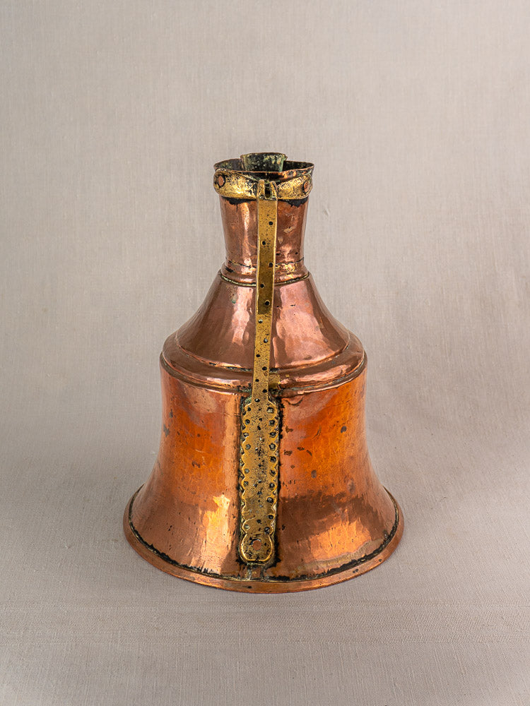 Antique French copper water jug with brass handle, flared base, and decorative brass side strip on neutral background.