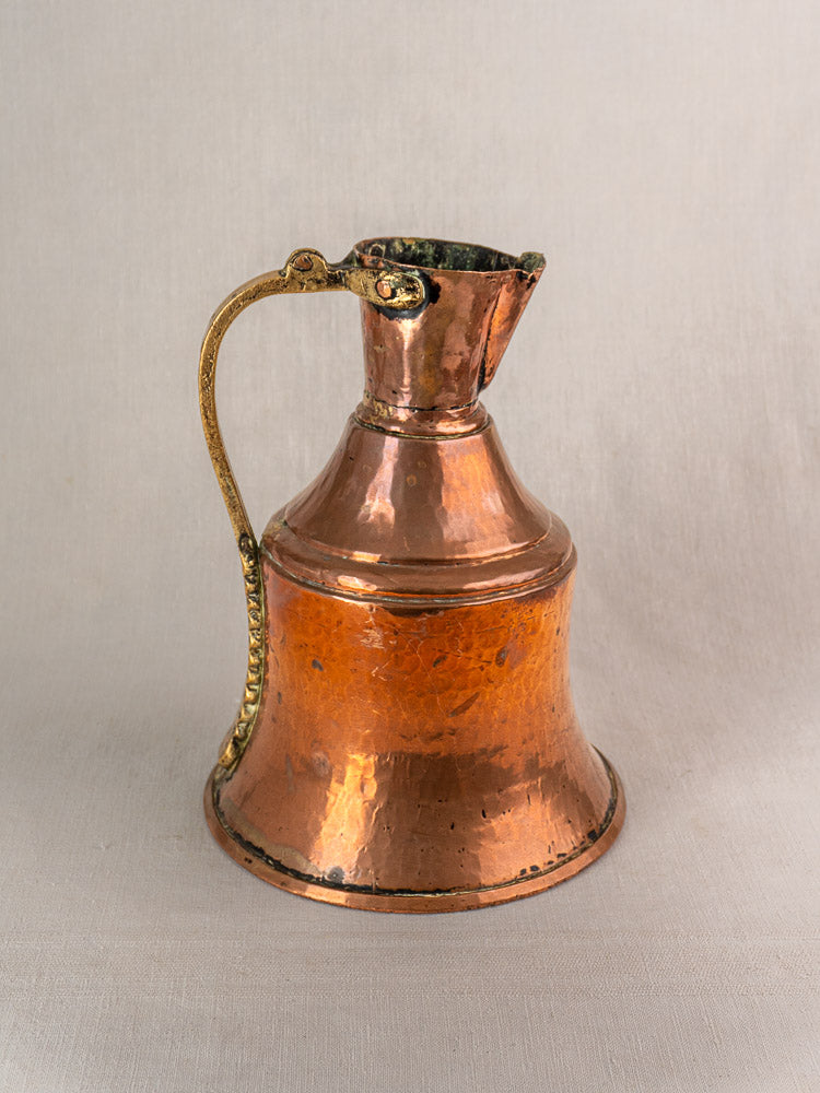 19th-century French copper water jug with brass handle, wide base, and narrow neck on a light background.