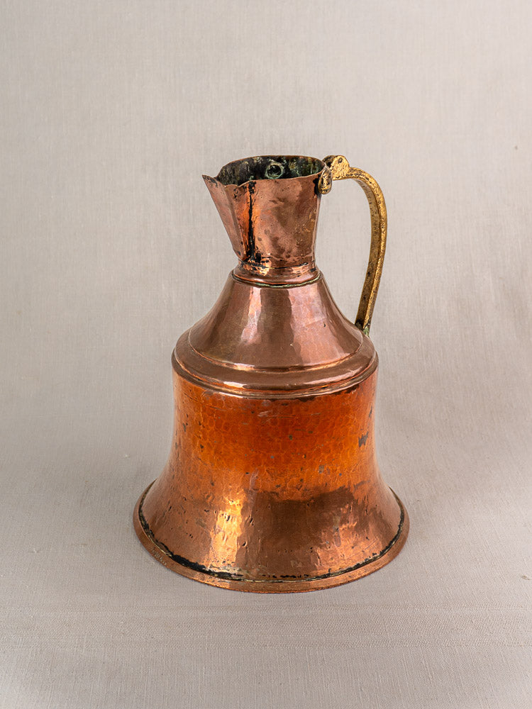 Antique French copper water jug with brass handle and narrow neck, set against a plain beige background.