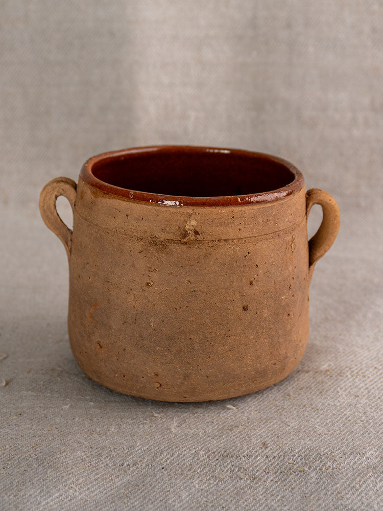 Late 19th century French confit pot with unglazed brown earthenware, twin handles, and glazed interior on gray fabric.