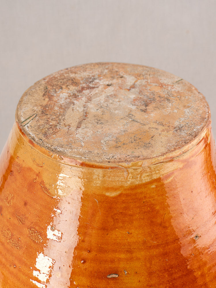 Antique French cruche base with glossy orange and honey-brown glaze, unglazed bottom, Provencal style, neutral background.