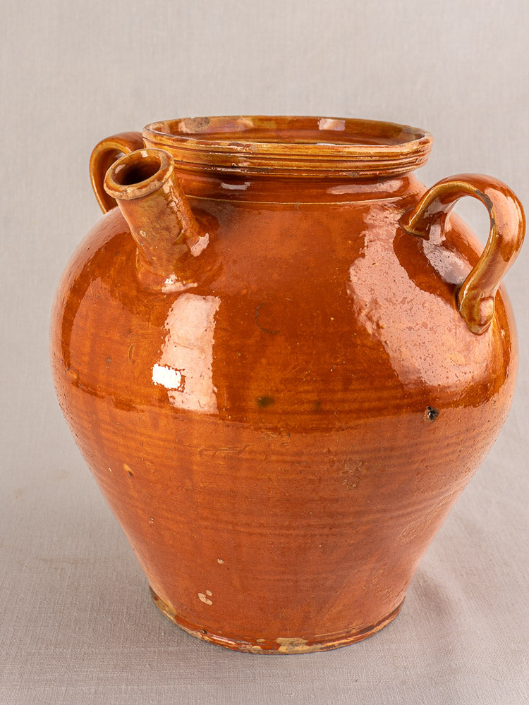 Large antique French cruche water jug, glazed earthenware with honey-brown finish, two handles, plain light background.