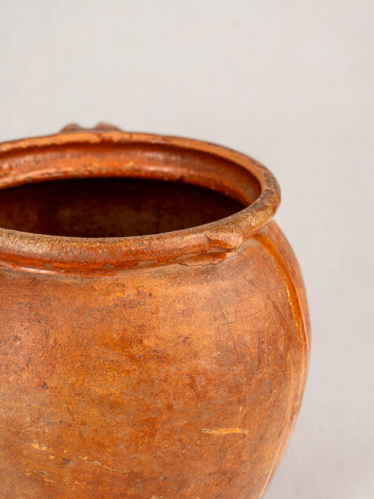 Antique French two-handle jug, 19th century glazed earthenware, rustic texture, uneven rim, set on a light background.