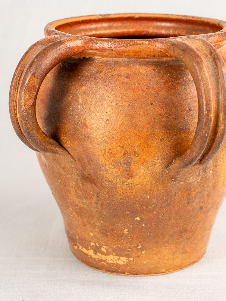 Antique French two-handle brown earthenware jug from 19th-century Southern France on a light surface, plain background.
