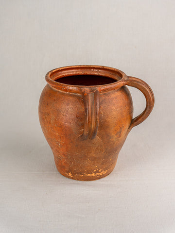 19th-century French glazed earthenware jug with two handles and narrow opening, on a neutral surface with light background.