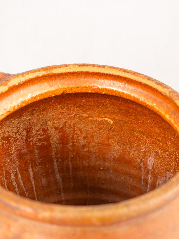 Antique French two-handle earthenware jug with reddish-brown glaze, textured vertical streaks, and a sandy-colored rim.