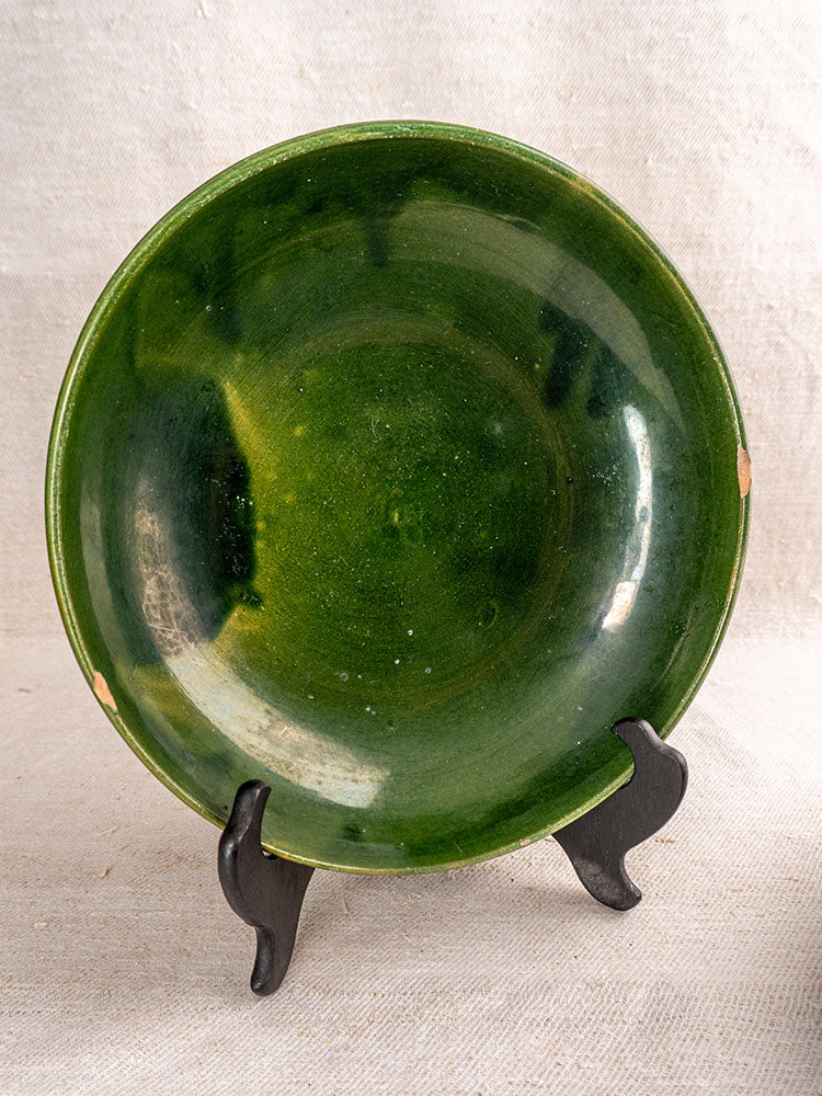 Pair of vintage French Provençal green glazed earthenware serving bowls with minor rim chips on black stands, beige fabric backdrop.