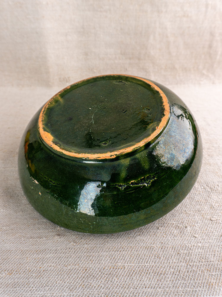 Pair of green glazed Provençal serving bowls with unglazed rims, vintage French pottery style, on light textured fabric.