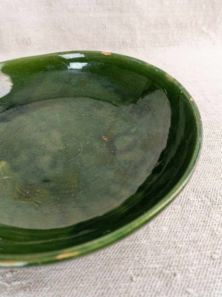 Pair of vintage green glazed Provençal serving bowls with glossy finish and minor rim chips on beige textured fabric.