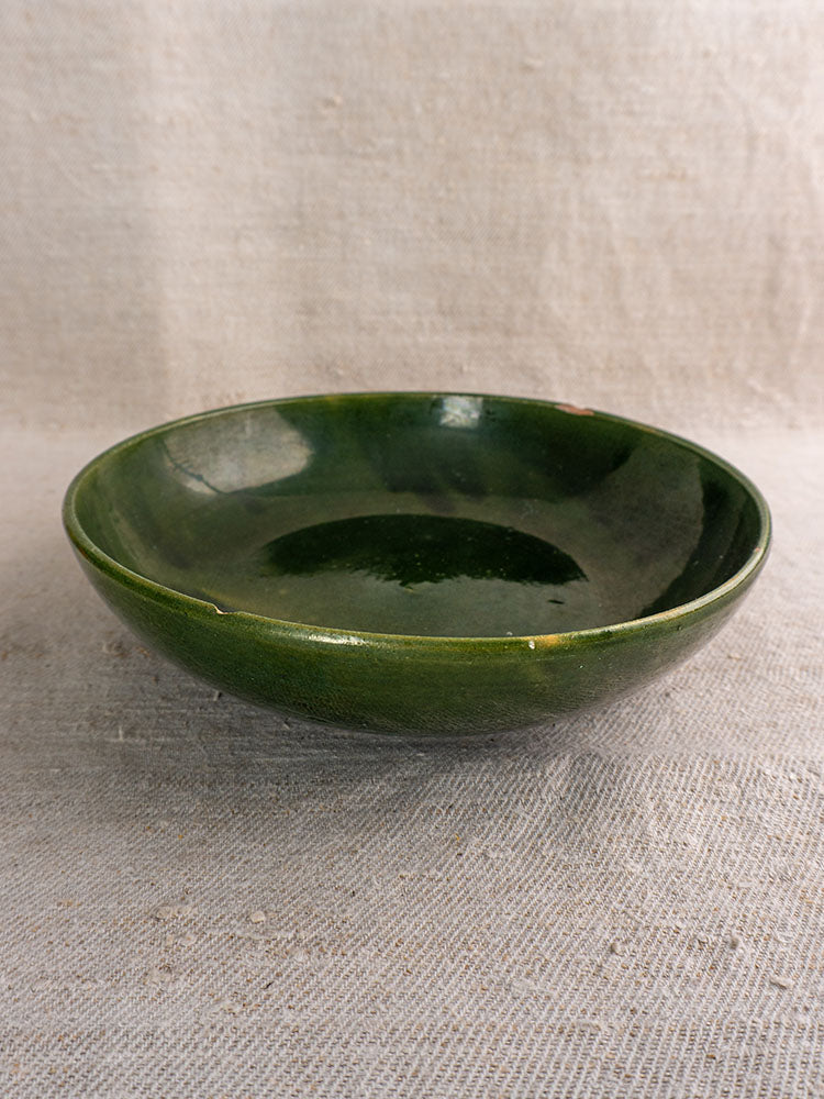 Pair of vintage green glazed Provençal serving bowls with glossy finish, set on textured beige fabric.