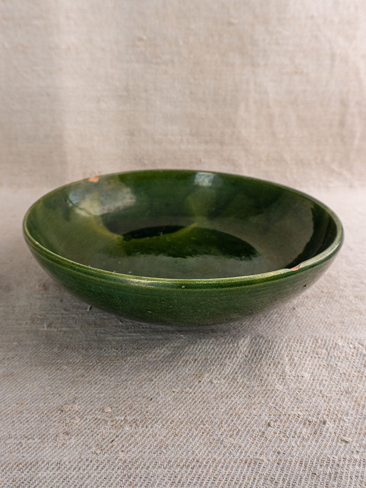 Green glazed vintage French Provençal serving bowls with glossy, handmade finish on textured linen cloth.