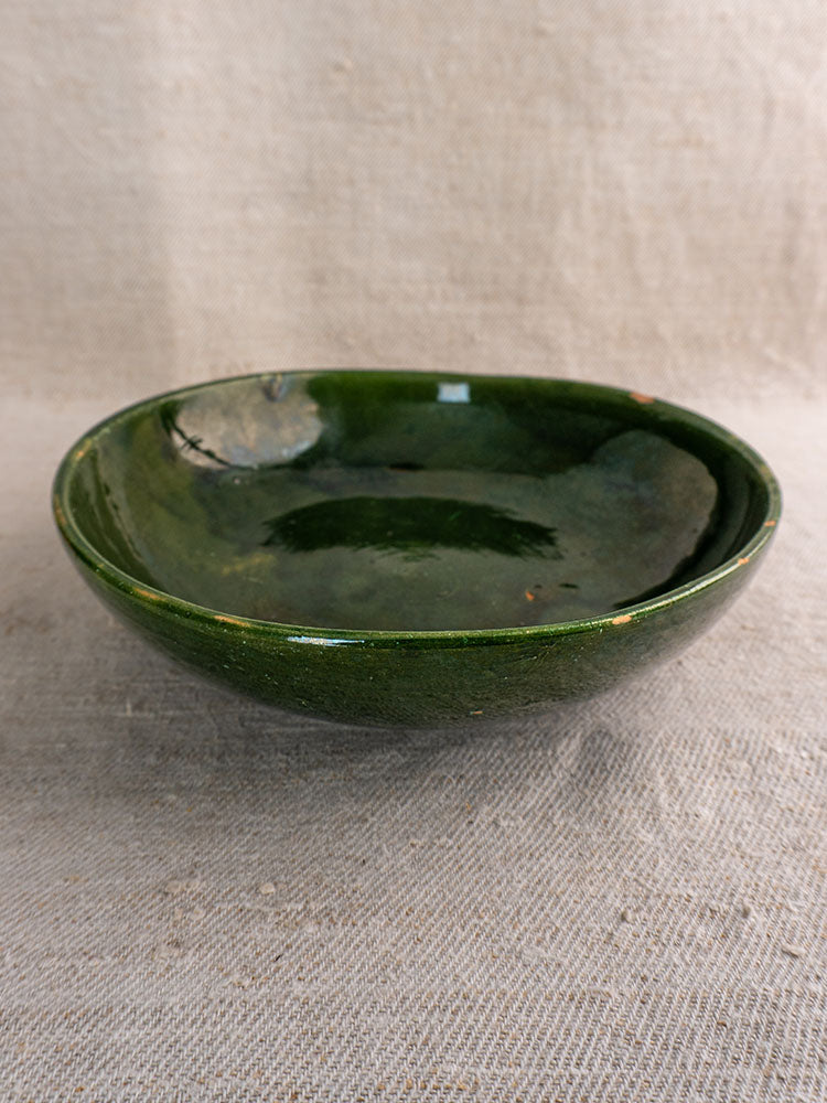 Pair of vintage French Provençal serving bowls with glossy green glaze displayed on textured beige fabric.