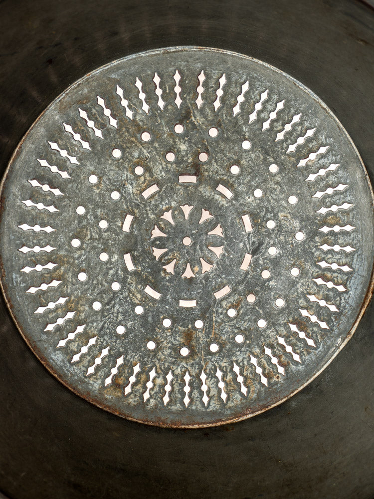 Antique French passoire in tinned sheet iron, pierced rosette base and circular pattern, overhead view.