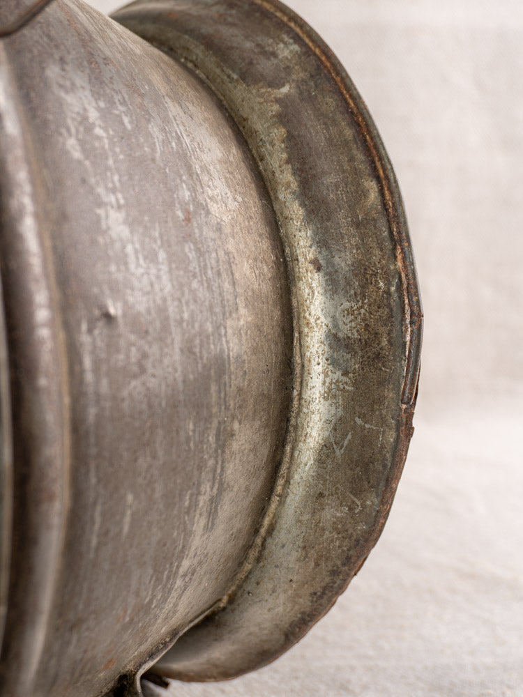 Antique French passoire in tinned sheet iron with a curved rim and pierced rosette base, vintage patina.
