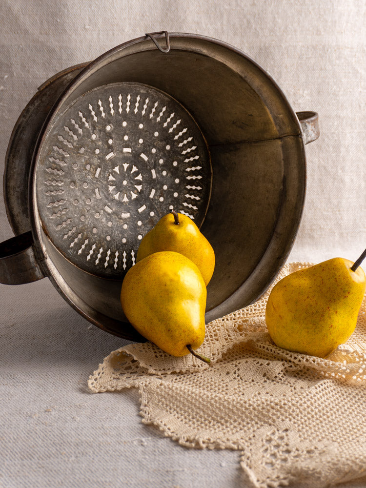Antique French tinned sheet iron passoire with pierced rosette base, pears, on crocheted cloth.
