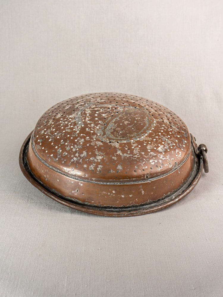 Antique French copper colander with domed perforated lid, side handle, and visible patina on plain background.