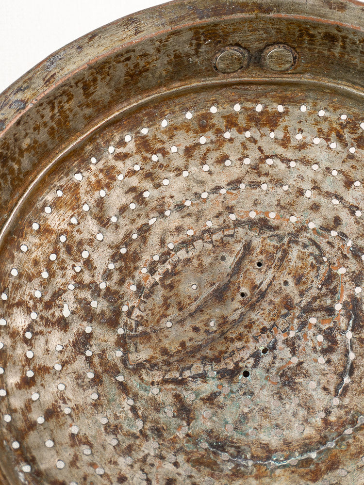Antique French copper colander with hand-tinned finish, showing rows of holes and weathered, textured surface.