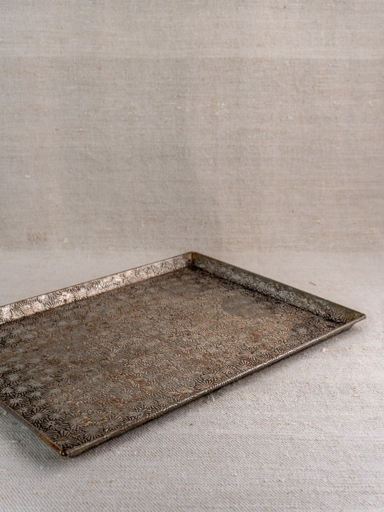 Vintage French Bakery Collection tinned steel tray with ornate patterns on textured beige fabric background.
