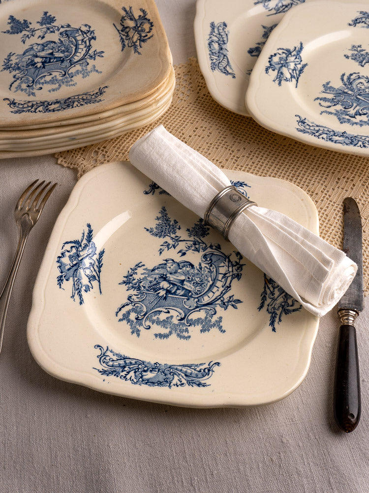 Set of 10 Antique French Clairefontaine plates, cream glaze with blue floral motifs, on lace placemat with linen napkin.