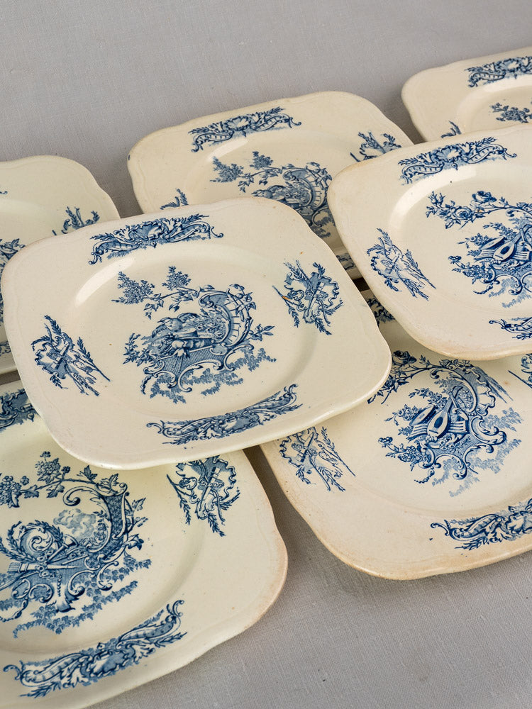 Set of 10 antique French Clairefontaine plates, Louis XV Terre de Fer, blue floral on cream, overlapping on a light surface.