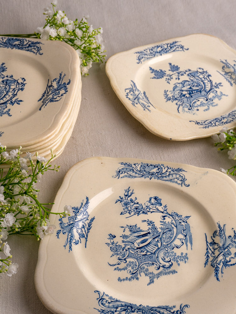 Set of 10 antique French Clairefontaine Louis XV Terre de Fer plates with blue floral patterns on wooden stands.