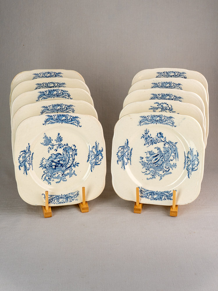 Set of 10 antique French Clairefontaine Louis XV Terre de Fer plates with blue floral patterns on wooden stands.