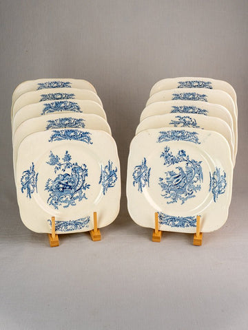 Set of 10 antique French Clairefontaine Louis XV Terre de Fer plates with blue floral patterns on wooden stands.