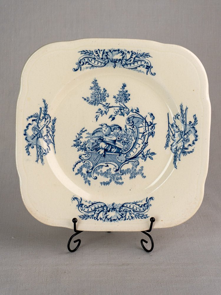 Vintage French Clairefontaine plate with blue Louis XV floral designs and cherub motif on a metal stand.