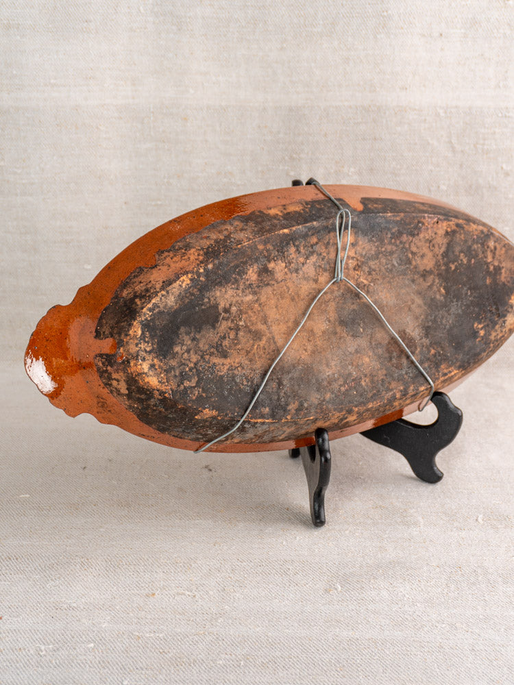 Antique French Saint-Uze Revol baking dish, late 19th century, oval, reddish-brown with black base on black stand.