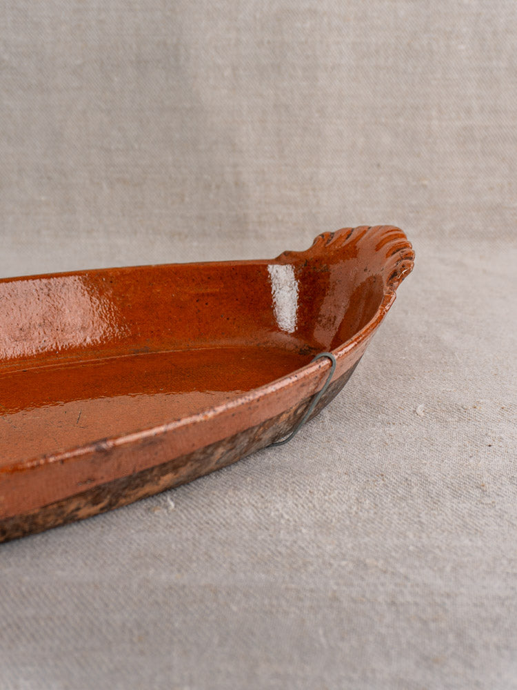 Antique French Saint-Uze Revol baking dish, late 19th century, scalloped edge, rich brown glaze on beige fabric.